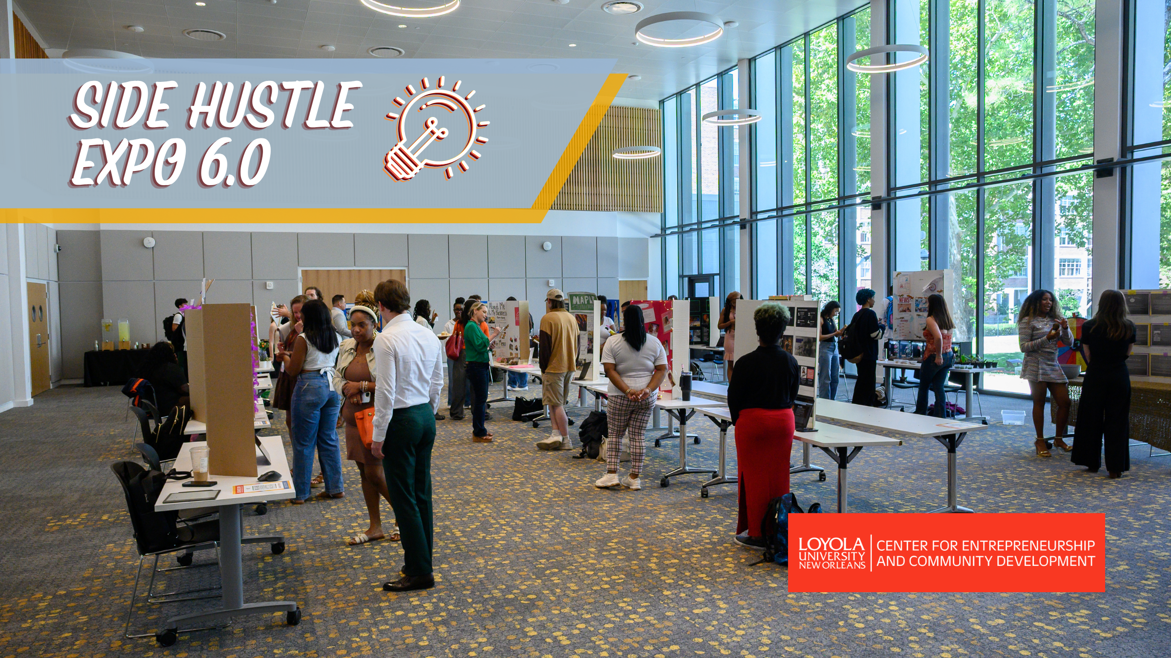 The St. Charles Room is filled with student entrepreneurs showcasing their businesses while visitors browse displays, ask questions, and support local ventures during Loyola's Side Hustle Expo.